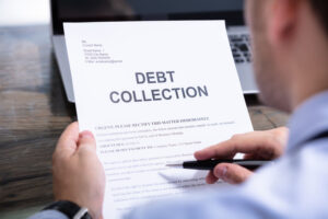 Man Reading Debt Collection Notice Letter At Desk