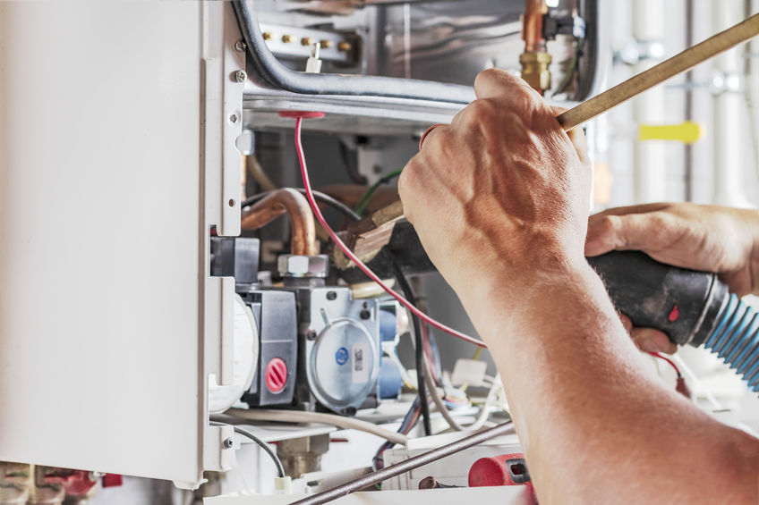 mechanic repairing gas boiler with a wrench